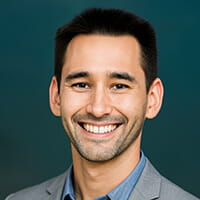 Bryan Krivo, Custom Products Engineering Lead at NuAire, in a professional headshot wearing a gray blazer and blue shirt, smiling against a blurred teal background.
