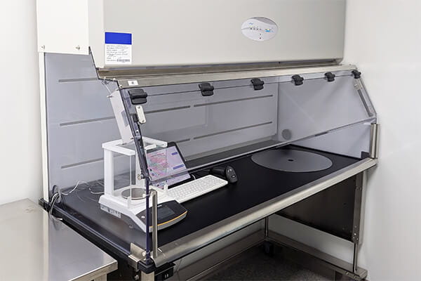 Custom NU-813 containment ventilated enclosure with extended work surface, in-workzone waste chute, and integrated scale, tablet, keyboard, and scanner for pharmacy hazardous drug handling.