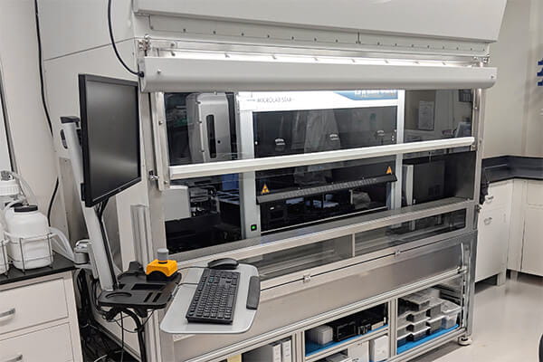 Custom NuAire NU-121 biosafety cabinet configured for robotic liquid handling, featuring integrated automation system, monitor, and ergonomic keyboard tray in a sterile lab environment.